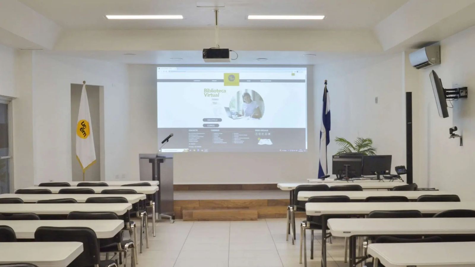 Auditorio con tarima, proyector y las banderas de UCEM y Nicaragua