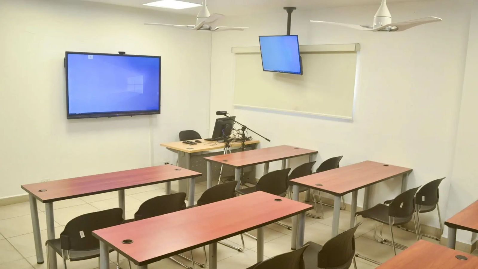 Aula con pantalla interactiva, cámara en trípode y micrófono