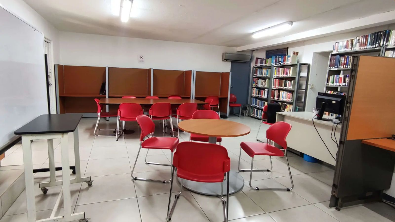 Biblioteca con mesas de estudio, cubículos y estantes de libros