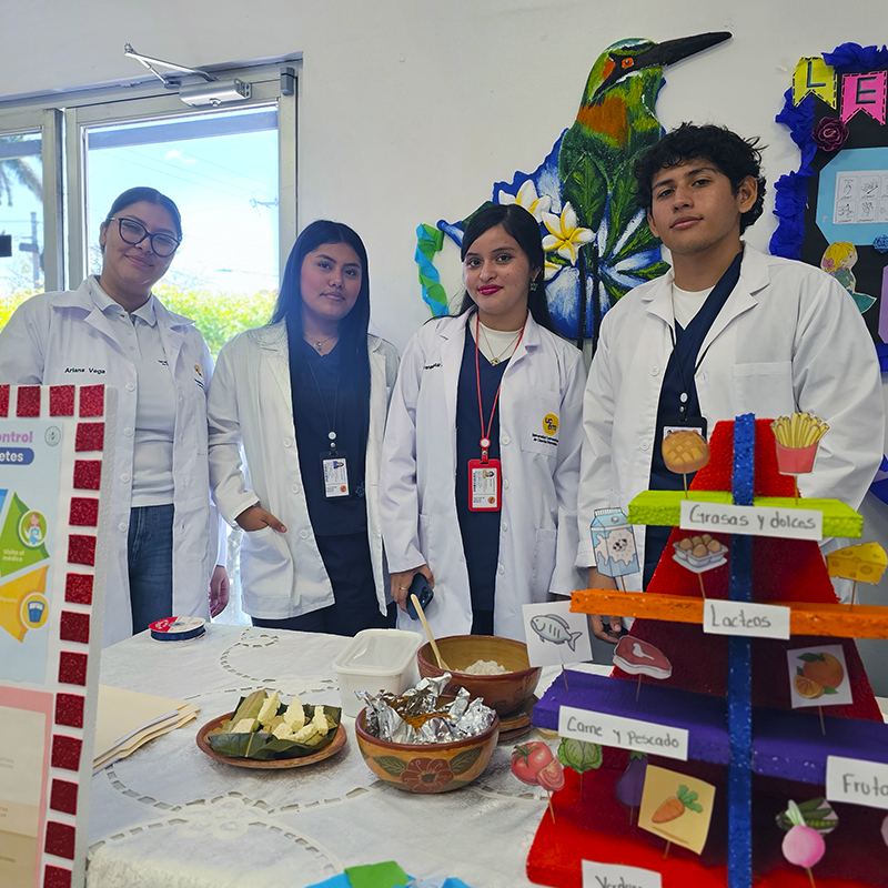 Estudiantes de nutrición junto a su pirámide de alimentos